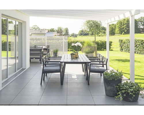 Terrass med trädgårdsbord, stolar och blomkrukor under en pergola