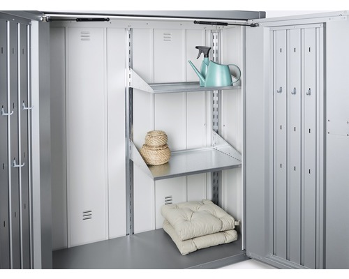 Insidan av ett metallförråd med hyllor, kuddar och en vattenkanna