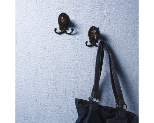 Två klädkrokar med djurmotiv på en vägg, en handväska hänger på en av krokarna