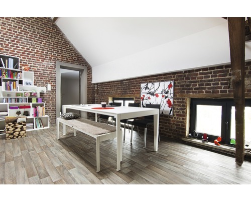 Ljust matrum med matbord, bänk, stolar och bokhylla mot tegelvägg