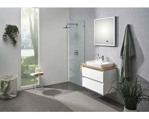 Modernt badrum med tvättställ, spegel, dusch och dekorationer.