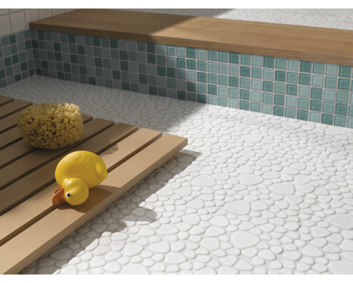 Badrum med golv av stenplattor, sittbänk med mosaikplattor och trägaller med badsvamp och badanka