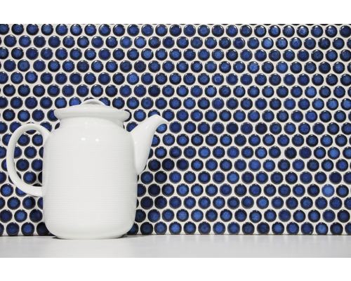 Mosaikplattor med runda, blå stenar och en vit tekanna
