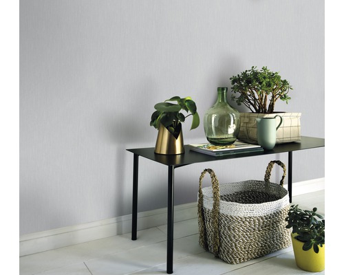 Rumsöversikt med bord, växter och dekoration framför en enfärgad vägg