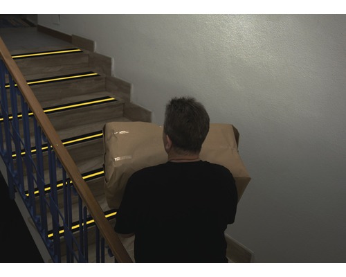 Man bär paket i trappa med halkskyddsremsor