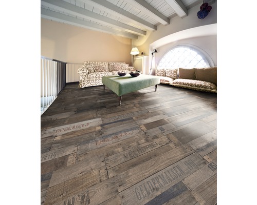 Vardagsrum med trägolv i plankdesign med inskriptioner, soffa och bord.