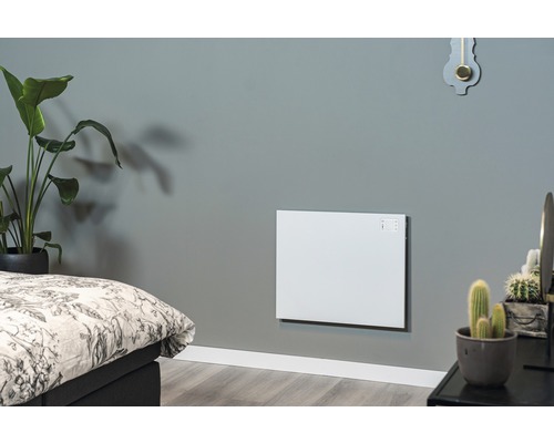 Vardagsrum med monterad, vit väggvärme bredvid en säng och växter