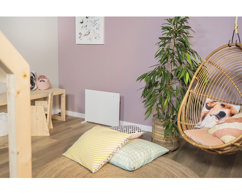 Vardagsrum med element, hängande korg, krukväxt och kuddar på en rund matta