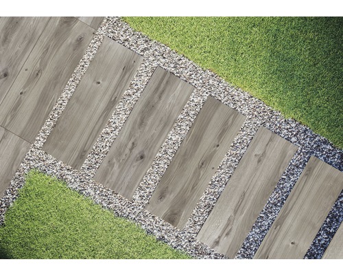 Trädgårdsscen med gångplattor i trälook, omgivna av grus och gräs