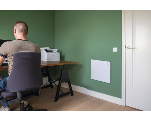 Kontor med värmepanel på väggen, skrivbord och kontorsstol.