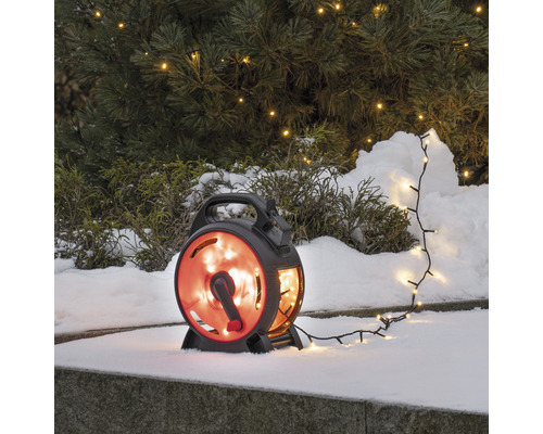 Ljusslinga med rulle i snön framför ett träd