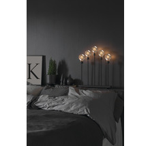 Dekorativ lampa med fem glödlampor på ett sängbord i sovrummet.