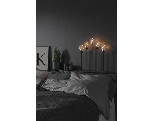 Dekorativ lampa med fem glödlampor på ett sängbord i sovrummet.