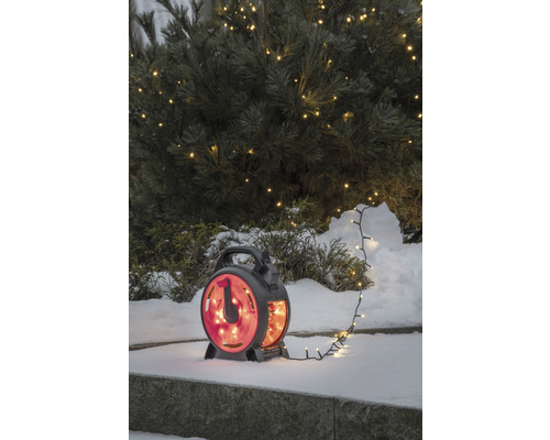 Ljusslinga på kabelvinda i snön framför ett upplyst träd