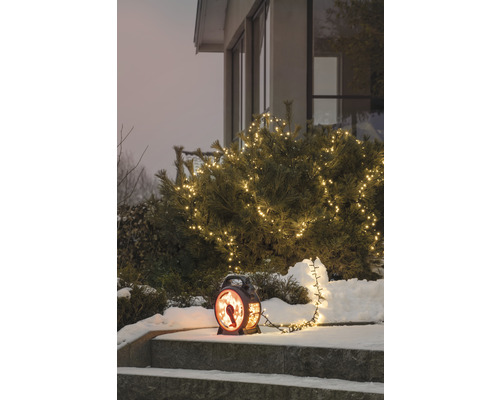 Vinterträdgårdsscen med upplyst buske och dekorativ lykta på en trappa