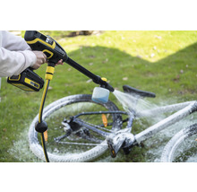 En person rengör en cykel utomhus med en sladdlös högtryckstvätt.