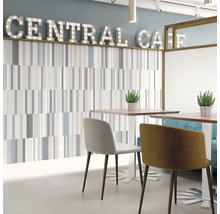 Ljust rum med väggplattor, bord och stolar i caféstil.