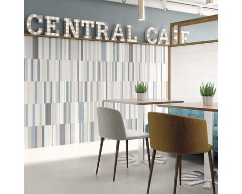 Ljust rum med väggplattor, bord och stolar i caféstil.