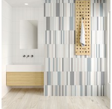 Badrum med handfat, spegel, handdukshängare och randig väggdesign