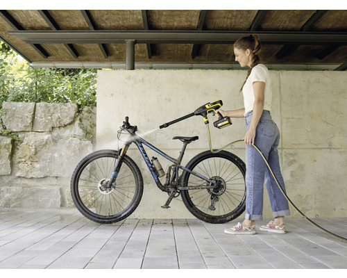 Kvinna rengör cykel med batteridriven högtryckstvätt