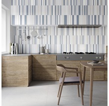 Köksscen med kaklat stänkskydd i randigt mönster, köksmöbler med träutseende och matbord med stol