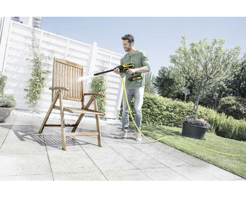 Man rengör trästol med batteridriven högtryckstvätt i trädgården