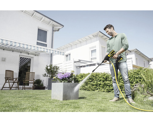 Man rengör en blomkruka i trädgården med en sladdlös högtryckstvätt.