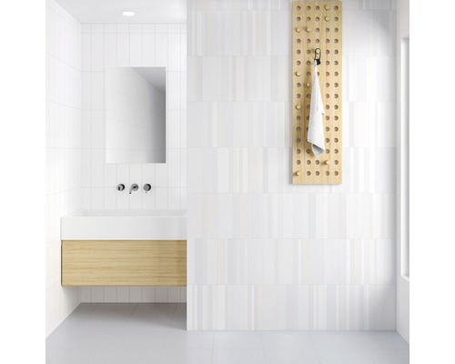 Ljust badrum med tvättställsskåp, spegel, handdukshängare och vita kakelplattor