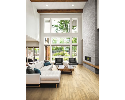 Ljust vardagsrum med soffa, fåtöljer, öppen spis och stort fönster