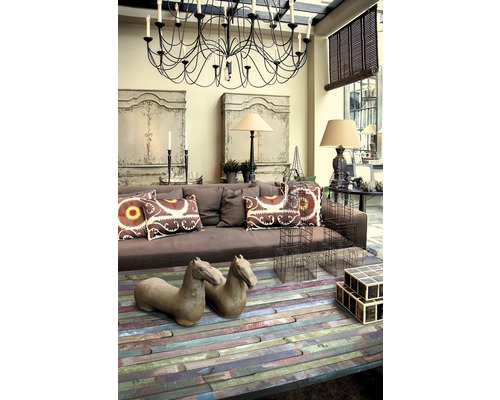 Vardagsrum med brun soffa, soffbord i trä, dekorativa föremål och ljuskrona.