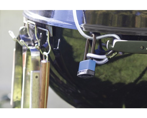 Detaljvy av en grill med grillverktyg och ett Habo-lås för säkerhet.