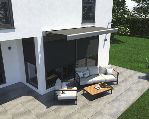 Uteplats med markis, soffa, fåtölj och bord framför ett hus.