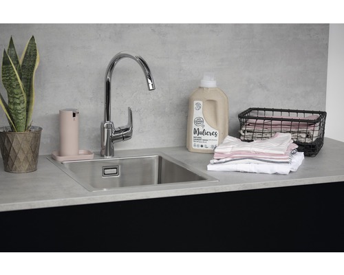 Tvättutrymme med diskho, kran, tvålpump, tvättmedel, tvättkorg och krukväxt