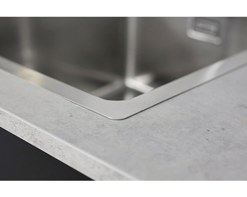 Detaljvy av en diskho i rostfritt stål i en bänkskiva.