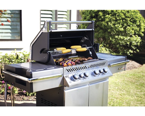 Grill med majskolvar och spettar i trädgården
