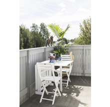 Balkongscen med vitt fällbord, stolar, dekorationer och en katt på balustraden