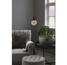 Vardagsrum med fåtölj, fotpall, bordslampa och krukväxt