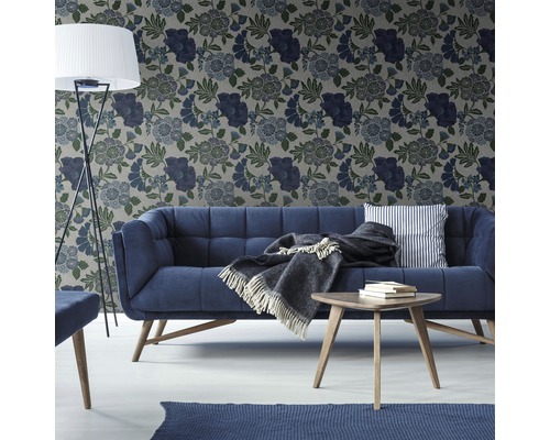 Vardagsrum med soffa, bord, golvlampa och blommönstrad tapet