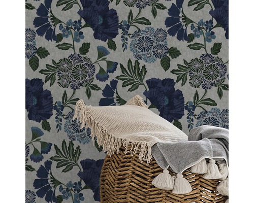 Närbild av en blommig tapet med kudde och filt i en flätad korg.