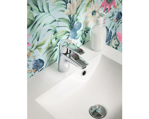 Tvättställ med blandare och tvålpump framför en blommig tapet