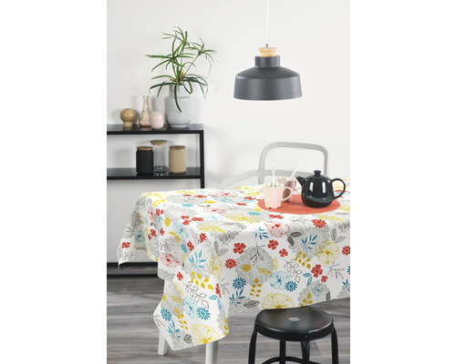 Matbord med vit duk och blomstermönster i ett ljust rum.