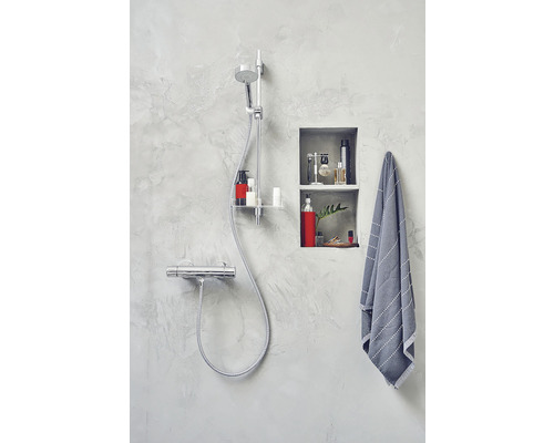 Badrum med duscharmatur, hylla och handduk i en modern design