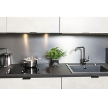 Modernt kök med diskho, spishäll, kastrull och växt