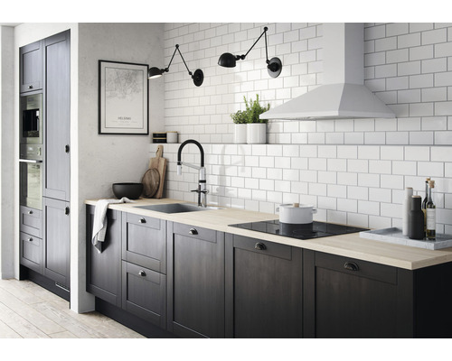 Köksscen med mörka skåp, diskho, kran, kokplatta och vita kakelplattor