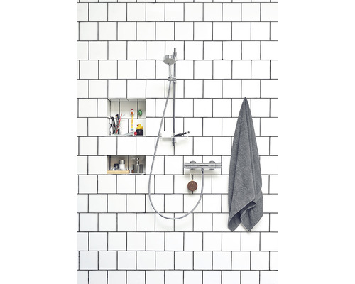 Badrum med vitkaklad duschkabin och duschblandare