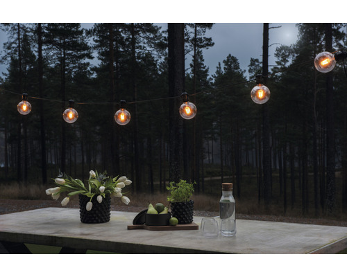 Scen med ljusslinga och bordsdekoration i trädgården