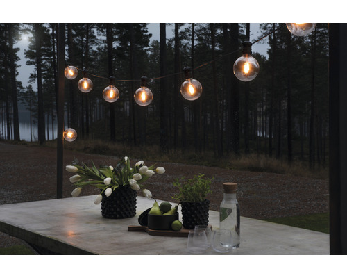 Scen med en ljusslinga ovanför ett bord med utomhusdekoration