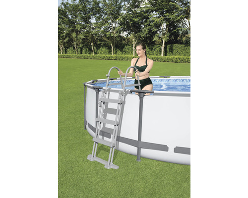 Ovanmarkspool med stege och kvinna i trädgården