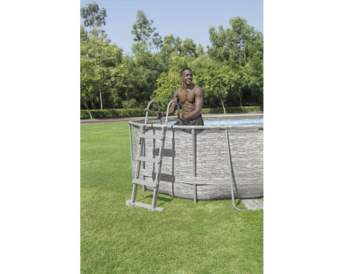 Ovanmarkspool med stege och person som står i trädgården