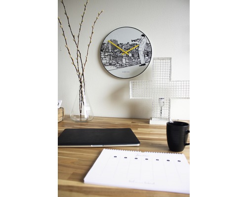 Dekorativt skrivbord med väggklocka, bärbar dator, kopp och kalender.